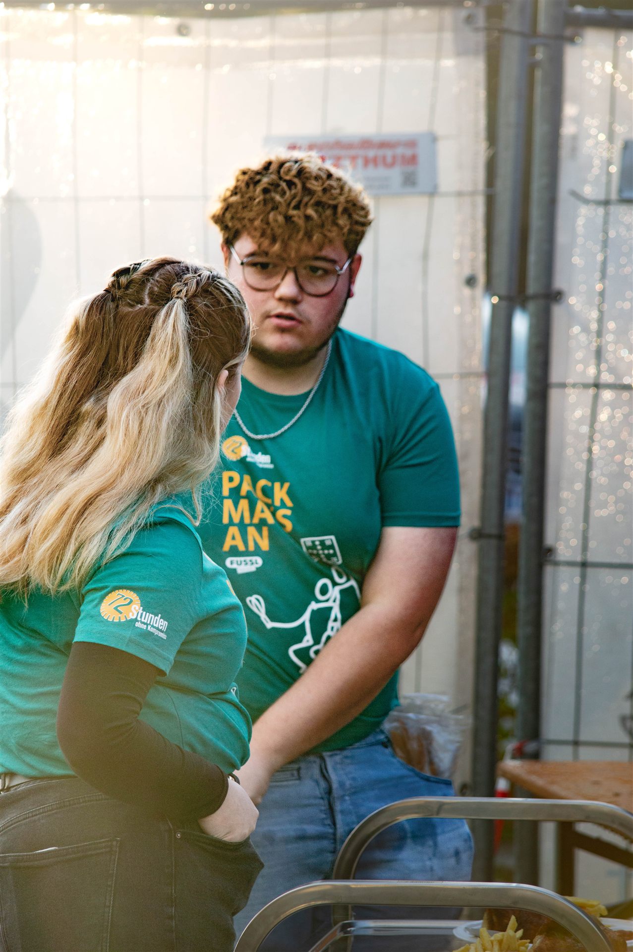 Helferin und Helfer im Pack-ma's-an-Shirt besprechen sich beim Aufbau