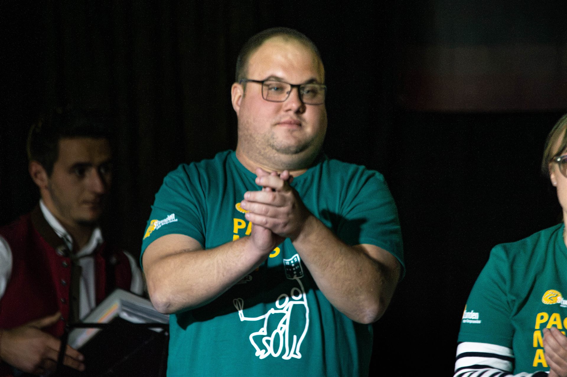 Moderator im Pack-ma's-an-Shirt applaudiert
