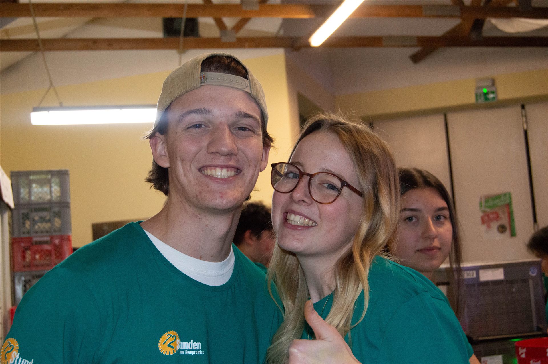 Helfer und Helferin in Pack-ma's-an-Shirts lächeln in die Kamera