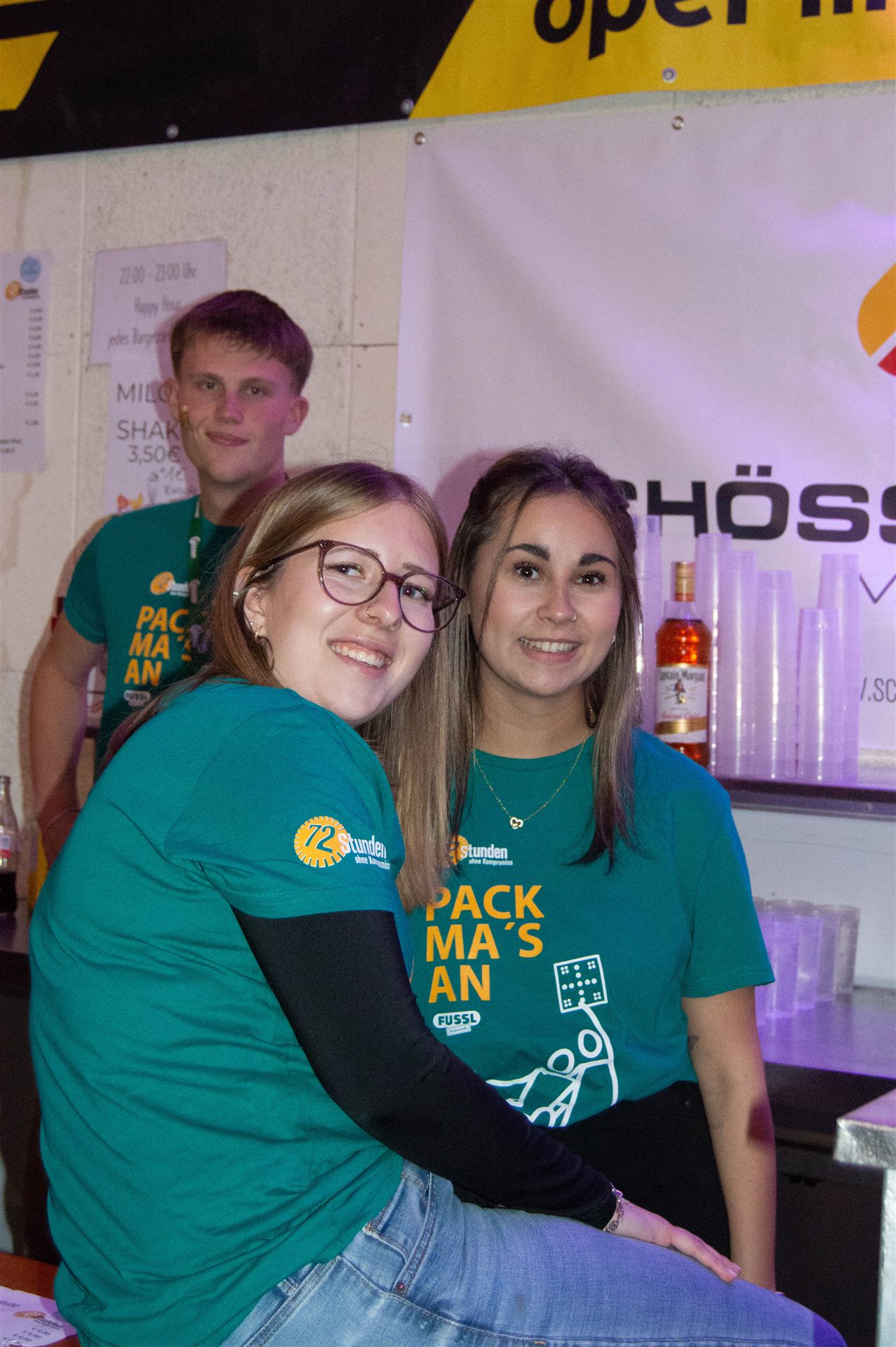Drei Helferinnen und Helfer in Pack-ma's-an-Shirts bei der Pause