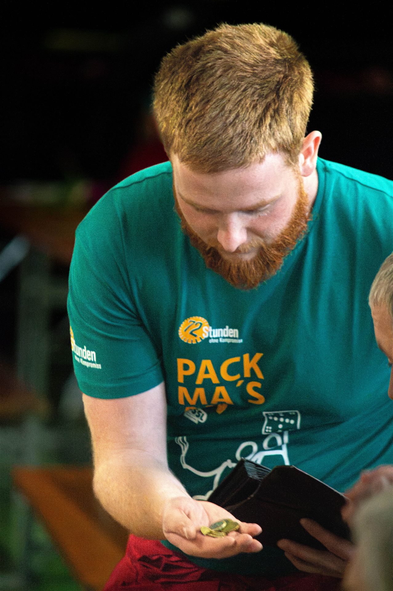 Helfer im Pack-ma's-an-Shirt mit Wechselgeld in der Hand